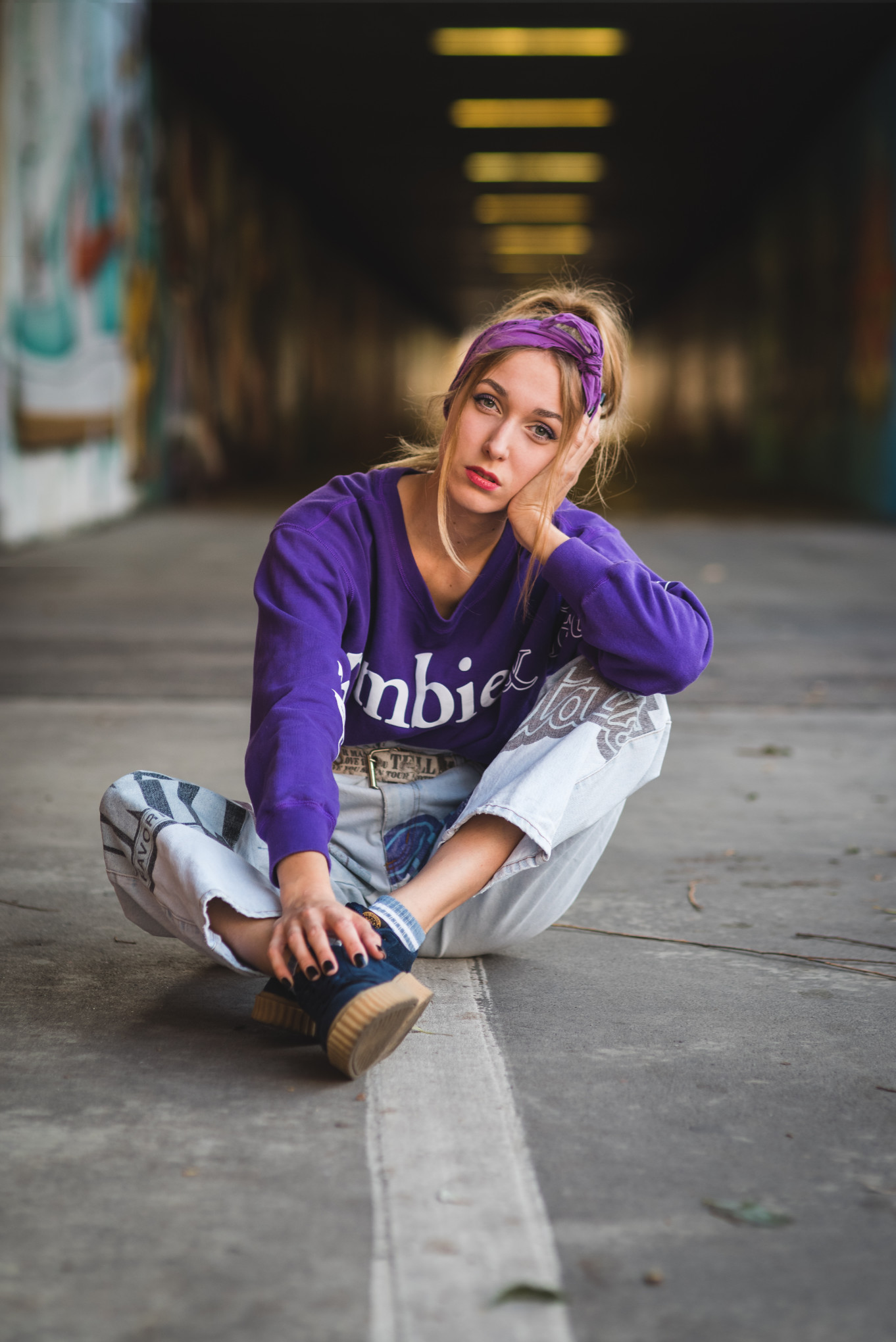 Miejska sesja lifestylowa w Poznaniu – portret dziewczyny w fioletowej bluzie w stylu streetwear siedzącej w tunelu