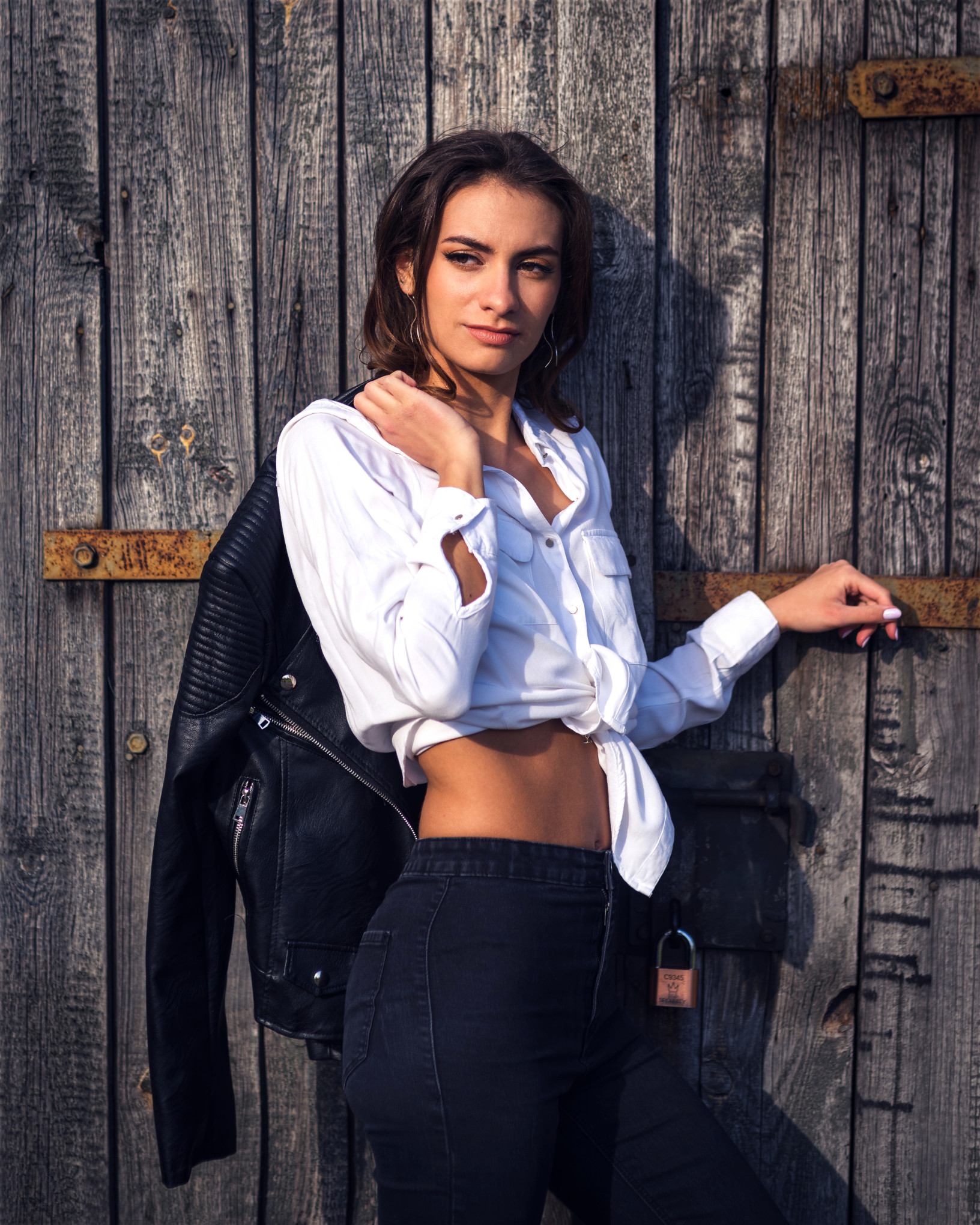 Naturalny portret kobiety w ramonesce i wiązanej koszuli, kadr z mocnym bocznym światłem w rustykalnym plenerze
