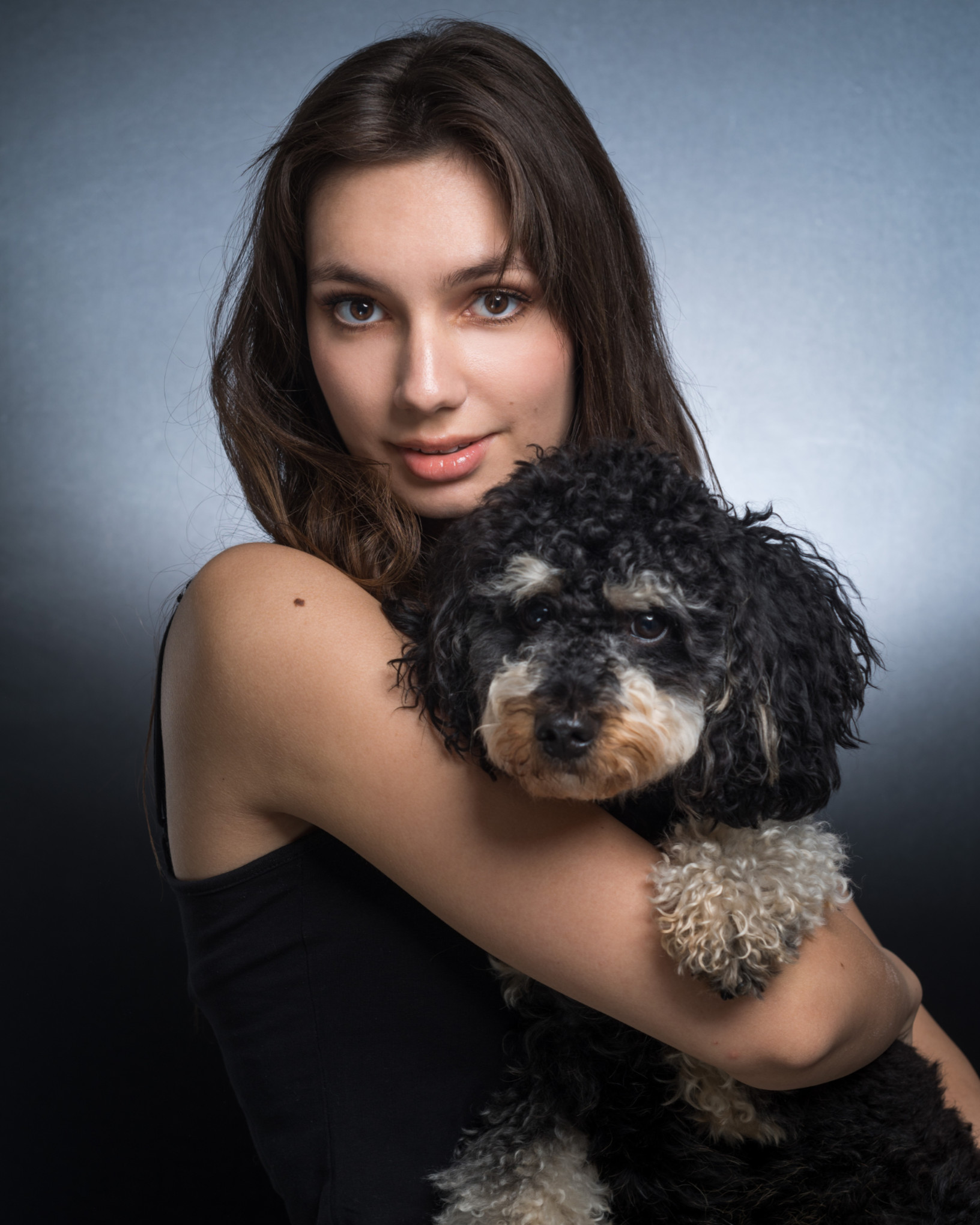 Bliski portret dziewczyny z psem maltipoo, klasyczne ujęcie studyjne na szarym tle z miękkim oświetleniem